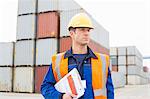 Mid adult man with clipboard in shipping yard