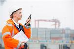 Side view of female engineer using walkie-talkie in shipping yard