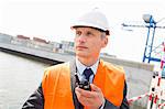 Middle-aged man using walkie-talkie in shipping yard