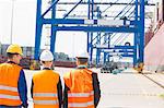 Rear view of workers walking in shipping yard