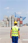Rear view of mid adult worker walking in shipping yard