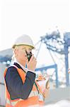 Female engineer using walkie-talkie in shipping yard