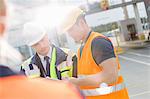 Male workers discussing over clipboard in shipping yard