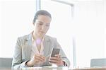 Young businesswoman using cell phone in office