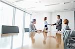 Businessman and businesswoman shaking hands in conference room