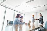 Businesspeople shaking hands in board room