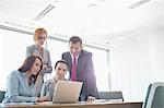 Businesspeople using laptop in conference room