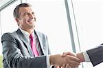 Smiling mature businessman shaking hands with partner in office