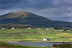 White croft cottages nestled in hamlet by mountain and Loch Vatten under grey clouds at Roag, Isle of Skye, Inner Hebrides and Western Isles, Scotland, United Kingdom, Europe