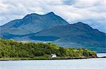 Solitary whitewashed croft cottage across the Sound of Sleat with Knoydart mountain behind, Isle of Skye, Inner Hebrides and Western Isles, Scotland, United Kingdom, Europe