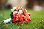 Bridal bouquet of various flowers on grass.