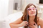 girl having fun pretending to fall in love with a pair of fake carton heart-shaped glasses