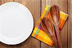 Wood kitchen utensils and empty plate over wooden table background with copy space