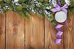 Christmas fir tree and bauble with purple ribbon on rustic wooden board with copy space