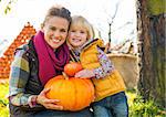 Portrait of happy mother and child holding pumpkin