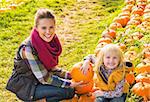 Portrait of happy mother and child among pumpkin