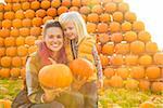 Portrait of happy mother and child holding pumpkins