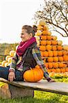Smiling young woman sitting with pumpkin