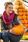 Portrait of happy young woman sitting with pumpkin