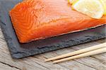 Fresh salmon fish with lemon on wooden table closeup