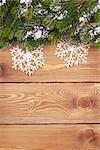 Christmas fir tree with snow and snowflake decor on rustic wooden board with paper for copy space