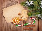 Christmas food and decor with snow fir tree over wooden table with paper for copy space