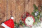 Christmas wooden background with clock, santa hat, snow fir tree and copy space