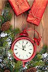 Christmas clock, gift boxes and snow fir tree over wooden background