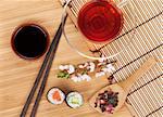 Sushi maki set, herbal tea and sakura branch over bamboo table