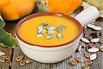 Pumpkin soup in ceramic bowl on old table closeup.