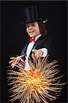 Young magician boy using his magic wand to conjure up sparks and fireworks