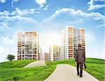 Businessman walks on road. Rear view. Buildings, grass field and sky in background. Business concept