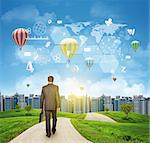 Businessman walks on road. Rear view. Buildings, grass field and sky with virtual elements. Business concept