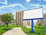 Tall buildings, green hills and road with large billboard against sky with clouds. Architectural concept