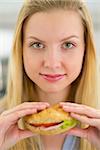 Portrait of young woman holding sandwich