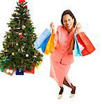 Excited african-american woman, holding shopping bags.  Full body isolated on white with Christmas tree in background.  .