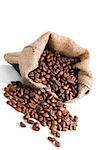 Fresh roasted coffee beans in brown sack isolated on white background. Culinary coffee drinking background.