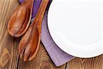 Wood kitchen utensils and empty plate over wooden table background with copy space