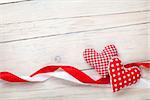 Valentines day background with toy hearts and ribbons over white wooden table background