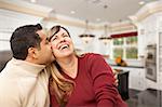 Happy Mixed Race Couple Kissing Inside Beautiful Custom Kitchen.