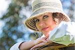 Woman in hat sitting on a wicker bench in the garden