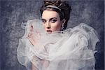 fashion shoot of pretty woman with romantic retro dame style. Wearing baroque dress with frill veil collar, precious earrings and tiara in the hair-style, elegant make-up