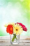 Colorful gerbera flowers on wooden table with summer sunny bokeh
