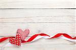 Valentines day background with toy hearts and ribbons over white wooden table background