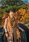 Portrait of smiling young woman standing near wooden barrel in autumn outdoors