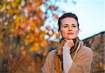 Portrait of thoughtful young woman standing in autumn outdoors in evening