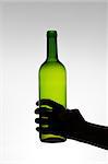 Silhouette of a hand holding a green wine bottle
