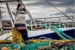 Woman is standing among fishing gear in a fishing village in Iceland