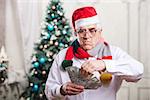 Senior man in Santa's hat holding money on Christmas background