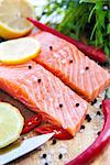 Raw salmon with lemon and pepper on cutting board